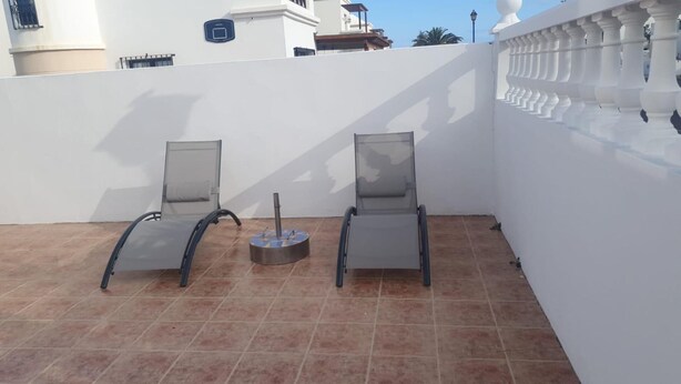 A rooftop terrace with two sun loungers and a small table, surrounded by white walls and a decorative balustrade. - Luxury Villa - Sleeps 4, Hottub Jacuzzi & Parking (Tías)