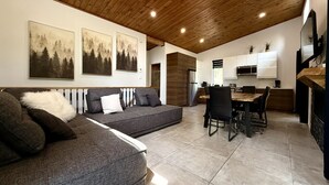 A modern living room with a sofa, dining table, and kitchen area.