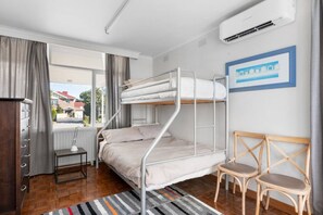 A bunk bed room with a desk, chair, and a view of houses outside. - Aloha Bayside - Highett (Highett)