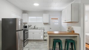 A compact kitchen with white cabinets, a stainless steel refrigerator, a microwave, and a coffee maker. - The Grove 1/2 mile from Boyne Mountain Sleeps 4 (Boyne Falls)