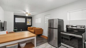 A compact kitchen with a wooden table, a stainless steel refrigerator, and a built-in oven. - The Grove 1/2 mile from Boyne Mountain Sleeps 4 (Boyne Falls)