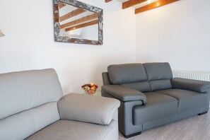 A living room with two sofas, a fruit bowl, and a mirror on the wall. - Morton Cottage - a cottage that sleeps 2 guests  in 1 bedroom (Thornhill)