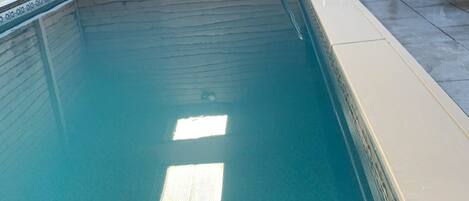 En swimmingpool med en træterrasse og en metalstige.