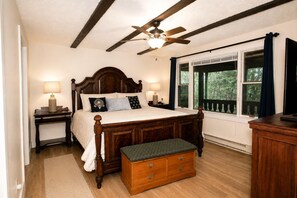 A bedroom with a wooden four-poster bed, a nightstand with a lamp, a bench with drawers, a ceiling fan, and a window with curtains. - Alpine Ridge Chalet | Grand Mountain Ski Retreat, Hot Tub & 3 Kitchens (Snowshoe)