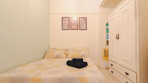 Un dormitorio con cama, armario y tres cuadros en la pared.
