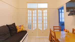 Una habitación con sofá, una mesa de comedor con sillas y un televisor montado en la pared.
