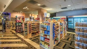 Une épicerie dont les rayons sont remplis d’en-cas et de boissons, avec un espace réfrigéré et une zone de caisse.