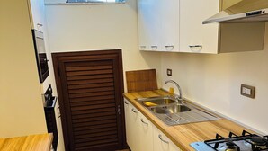 A compact kitchen with a wooden countertop, stainless steel sink, and a gas stove. There is a window above the sink and a door leading to another room. - Relaxation with Jacuzzi and pool between Pompeii Amalfi coast, Sorrento and Capri (Trecase)