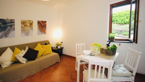A living room with a sofa, chairs, a table, and a window with a view of greenery. - Relaxation with Jacuzzi and pool between Pompeii Amalfi coast, Sorrento and Capri (Trecase)