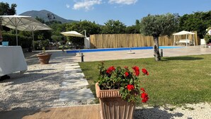 A poolside area with umbrellas, seating, and a wooden deck. - Relaxation with Jacuzzi and pool between Pompeii Amalfi coast, Sorrento and Capri (Trecase)