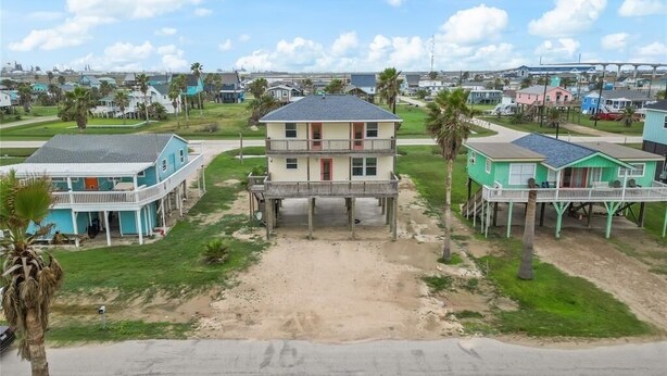A coastal residential area with houses featuring balconies and a sandy driveway. - The Neon Palm - 4bed 3bath in Surfside Beach TX (Freeport)