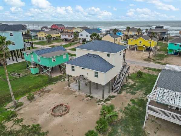 A coastal residential area with houses on stilts, a sandy beach, and a view of the ocean. - The Neon Palm - 4bed 3bath in Surfside Beach TX (Freeport)