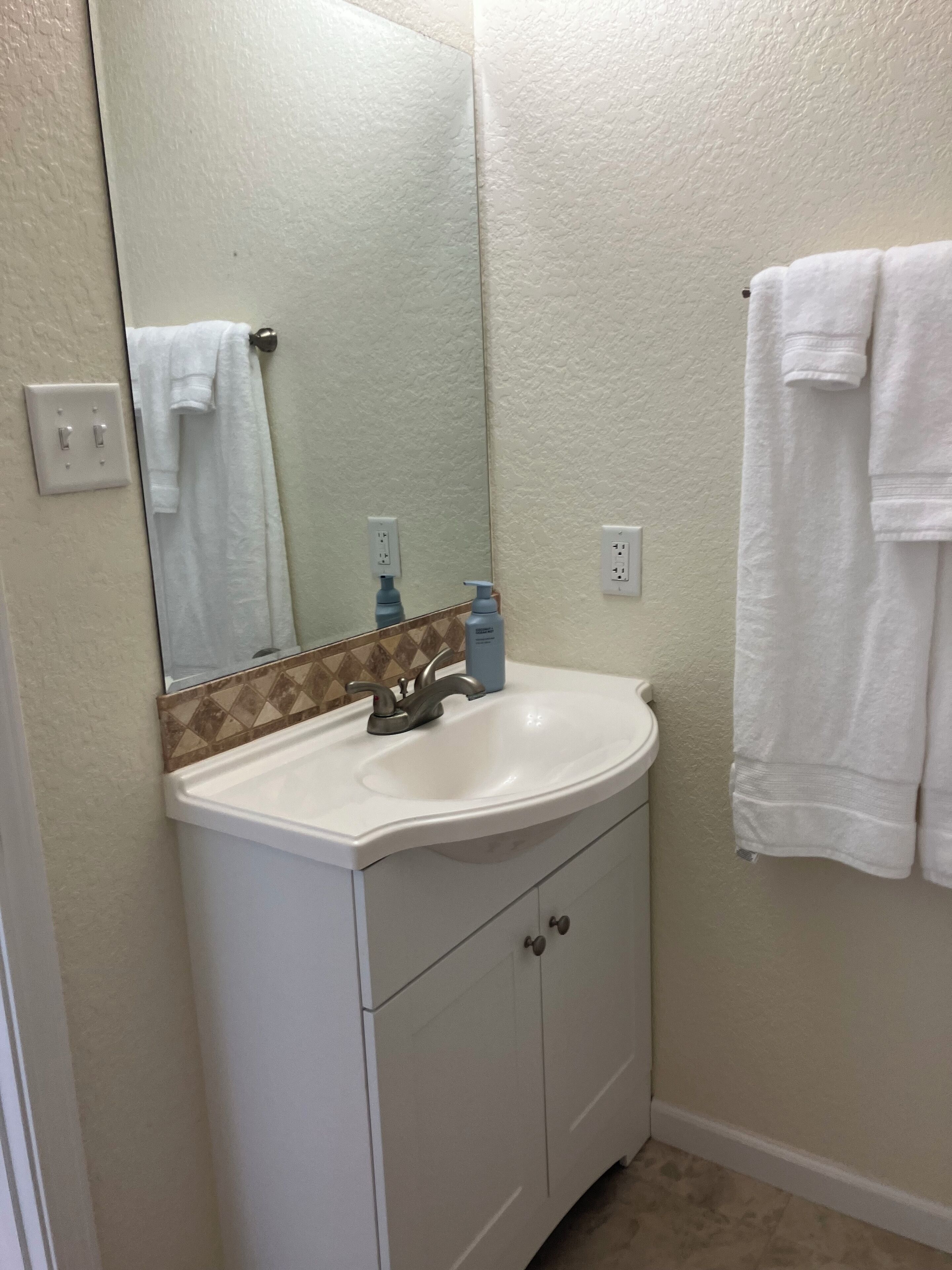 A bathroom with a white sink, a mirror, and a towel rack.