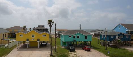 A coastal residential area with colorful houses, a sandy driveway, and a clear sky.