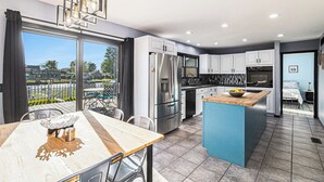 Una cocina moderna con electrodomésticos de acero inoxidable, una mesa de comedor de madera y vistas al exterior.