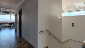 Un intérieur épuré et moderne, avec un escalier, une vue sur l’extérieur et un panneau indiquant la sortie.