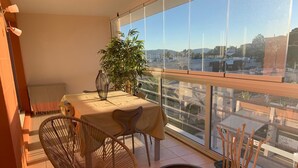 A balcony with a dining table, chairs, a potted plant, and a small round table. - Comfortable apartment 95 m2, 2 terraces, sea view, near beach, port, center (Cavalaire-sur-Mer)