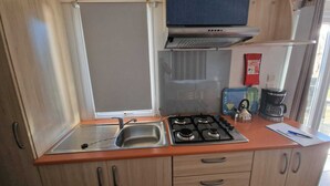 A compact kitchen with a gas stove, a sink, and a coffee maker.