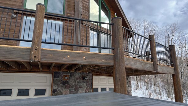 A wooden deck with a stone wall and a garage.