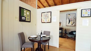 Un comedor con una mesa redonda dispuesta para dos personas, sillas, una botella de vino y un cuadro en la pared.