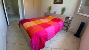 Ein Schlafzimmer mit einem Bett, einem Kleiderschrank, einem Nachttisch und einem kleinen Regal.