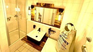 Un baño con cabina de ducha de vidrio, un lavabo con encimera de madera y un espejo con marco de madera.