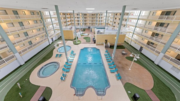 Een hotel met meerdere verdiepingen, een centraal gelegen zwembad, terrasjes en een binnenplaats.