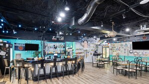 Een bar met een toonbank, krukken en verschillende flessen en glazen.