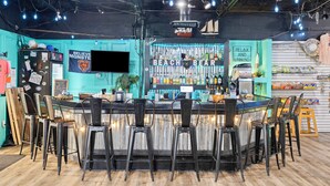 Een bar met een toonbank, krukken en verschillende flessen en glazen.