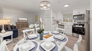 Een moderne keuken met witte kasten, een roestvrijstalen oven en een magnetron.
