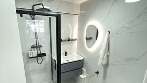 A modern bathroom with a glass shower enclosure, a vanity with a mirror, and a toilet.