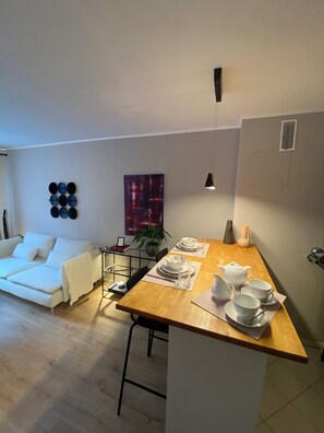 A modern living room with a sofa, a coffee table set with tea and cups, and a dining area with a wooden table. - Casa Soden ~ Artistic Living Near Frankfurt (Bad Soden am Taunus)