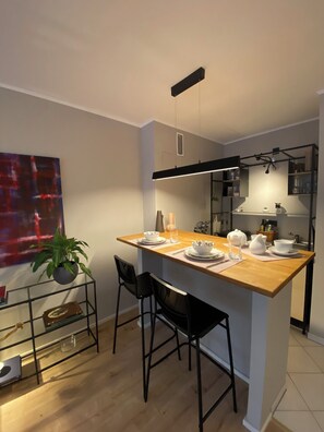 A modern kitchen with a wooden island, black chairs, and a dining table set for four.