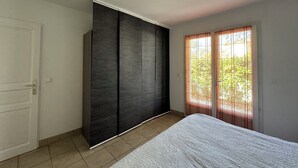 Une chambre à coucher comprenant un lit, une armoire et une porte-fenêtre coulissante donnant sur un balcon.