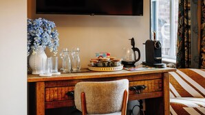 A wooden desk with a television above it, a coffee maker, and various glassware and decorative items. - Unique Shrewsbury Rooms (Shrewsbury)