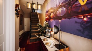 A staircase with a red carpet, a wall-mounted light fixture, and a framed picture on a table with a lamp. - Unique Shrewsbury Rooms (Shrewsbury)