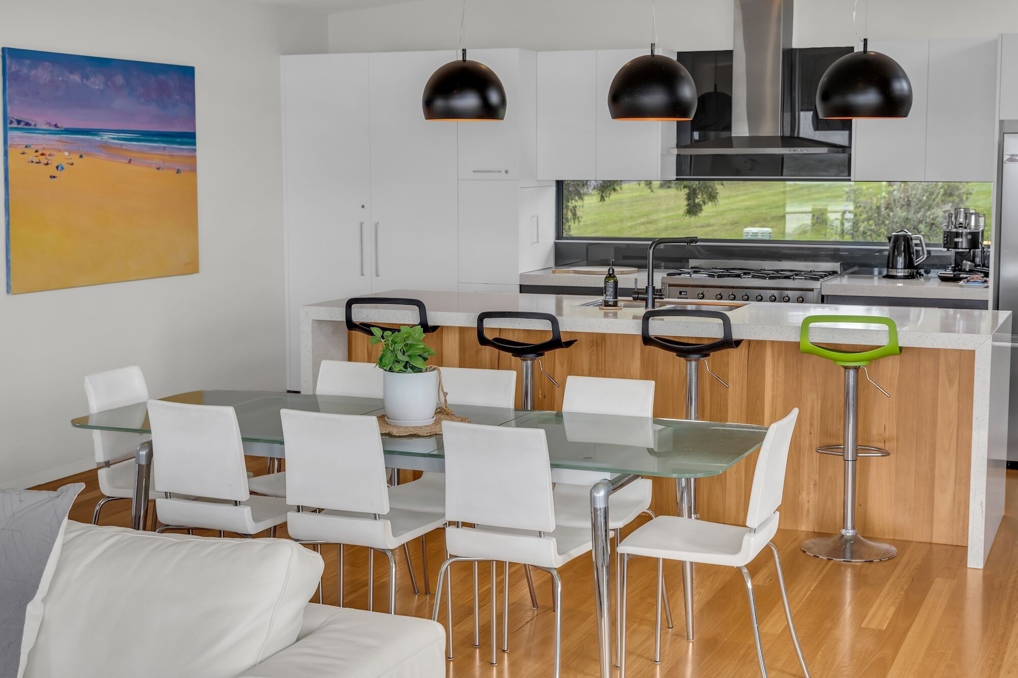Une cuisine moderne dotée d’un grand îlot central, de meubles blancs et offrant une vue sur l’extérieur.