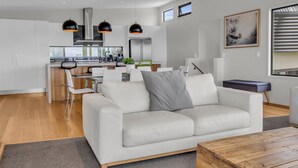 A modern living room with a white sofa, a coffee table, and a kitchen area in the background.