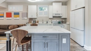 Une cuisine moderne avec des meubles blancs, un îlot central doté de sièges et une table à manger.