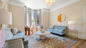 A living room with a blue sofa, a round coffee table, and a patterned rug.