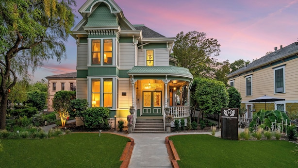 A Victorian-style house with a well-maintained lawn, a front porch, and a visible front door.
