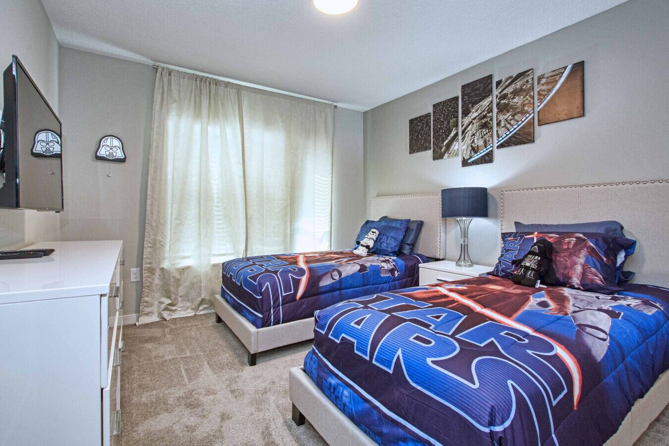 A bedroom with two beds, a desk, and a TV.