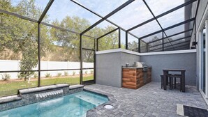 Un jardin avec un jacuzzi, un espace barbecue et une table pour s’asseoir.