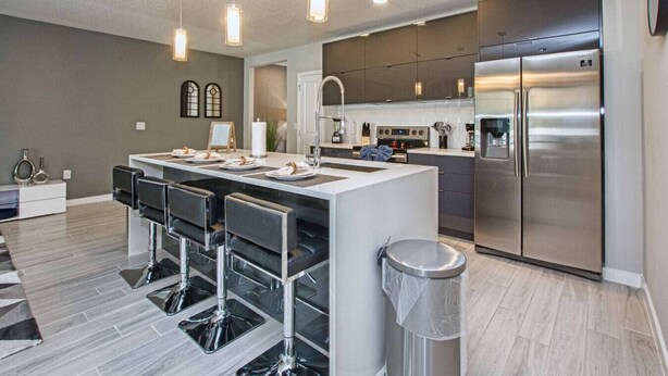 Une cuisine moderne dotée d’un îlot central, d’appareils électroménagers en acier inoxydable et de tabourets de bar.