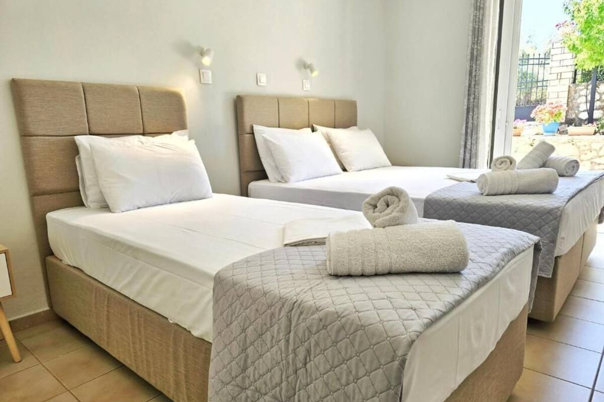 A hotel room with two beds, each with a headboard and pillows. There are towels on the beds.