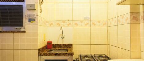 A compact kitchen with a gas stove, oven, and a small refrigerator.