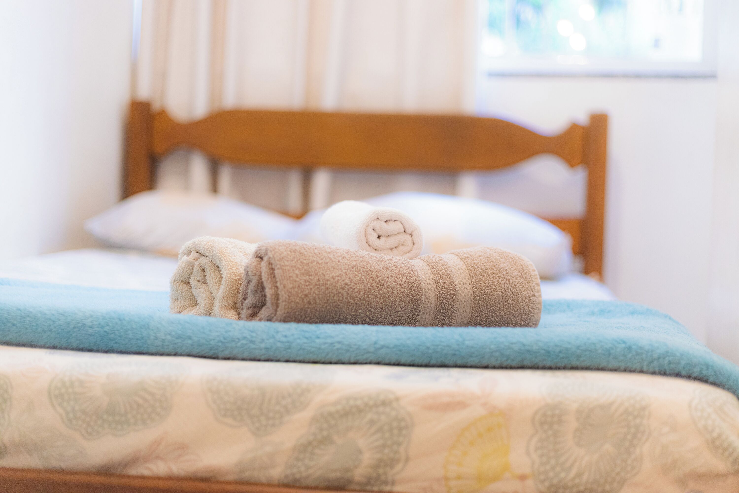 A neatly made bed with a blue blanket and a patterned duvet.