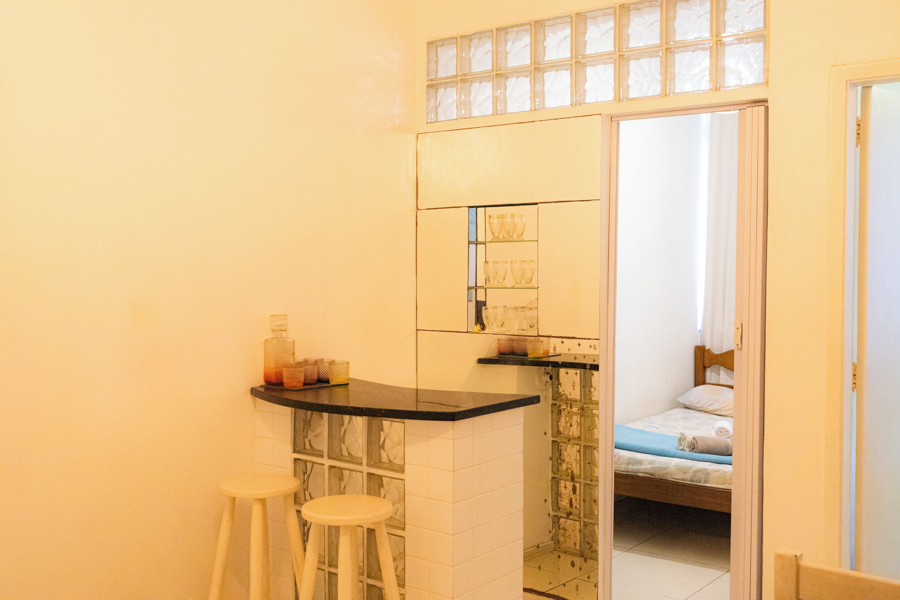 A bathroom with a mirror, a sink, and a toilet. There is a small stool next to the sink.
