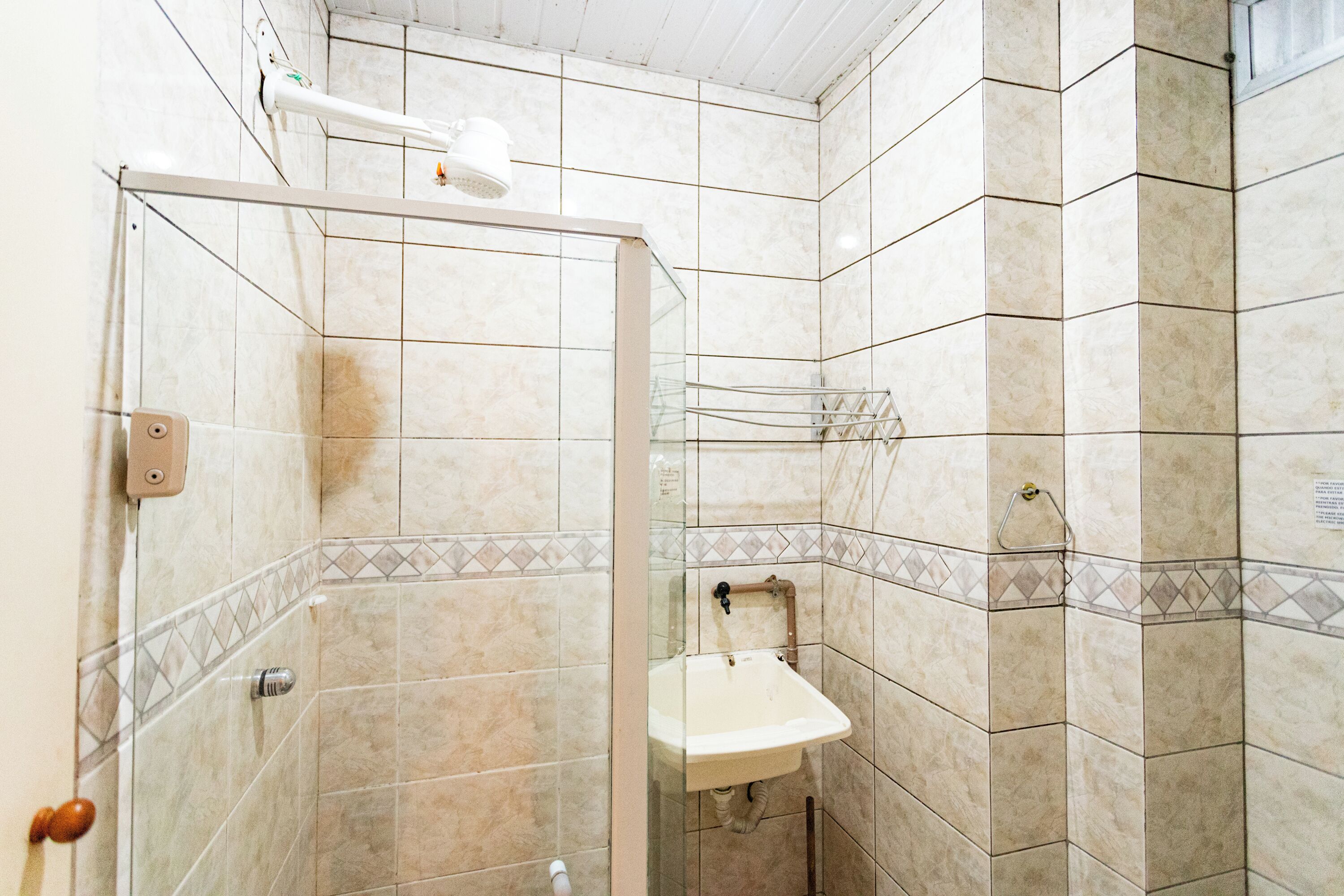 A bathroom with a glass-enclosed shower, a sink, and tiled walls.