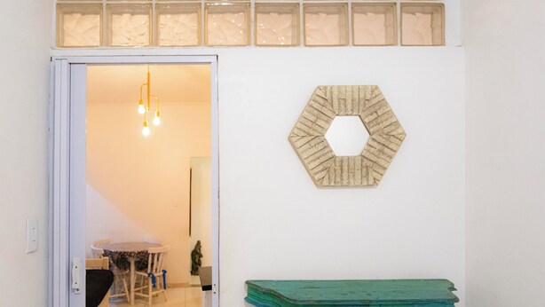 A room with a wooden hexagonal wall decoration, a green table, and a door leading to another room with a table and chairs. - 360 Copa Beach NSC By SUHCasa (Rio de Janeiro)